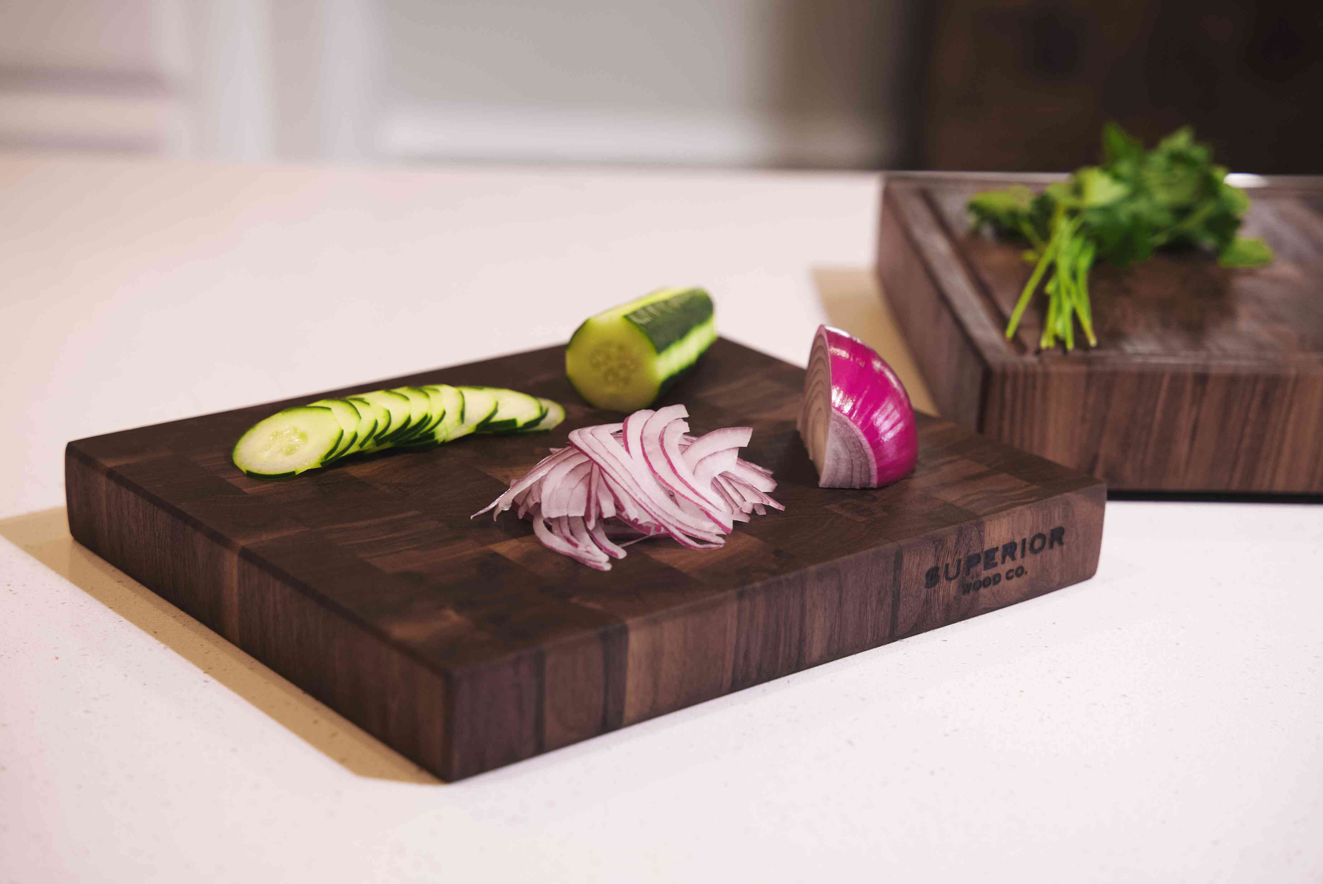 medium end grain cutting board with red onions and cucumbers